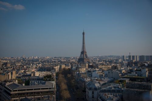 Free Panoramic view of the Eiffel Tower surrounded by Paris cityscape under a clear blue sky. Stock Photo