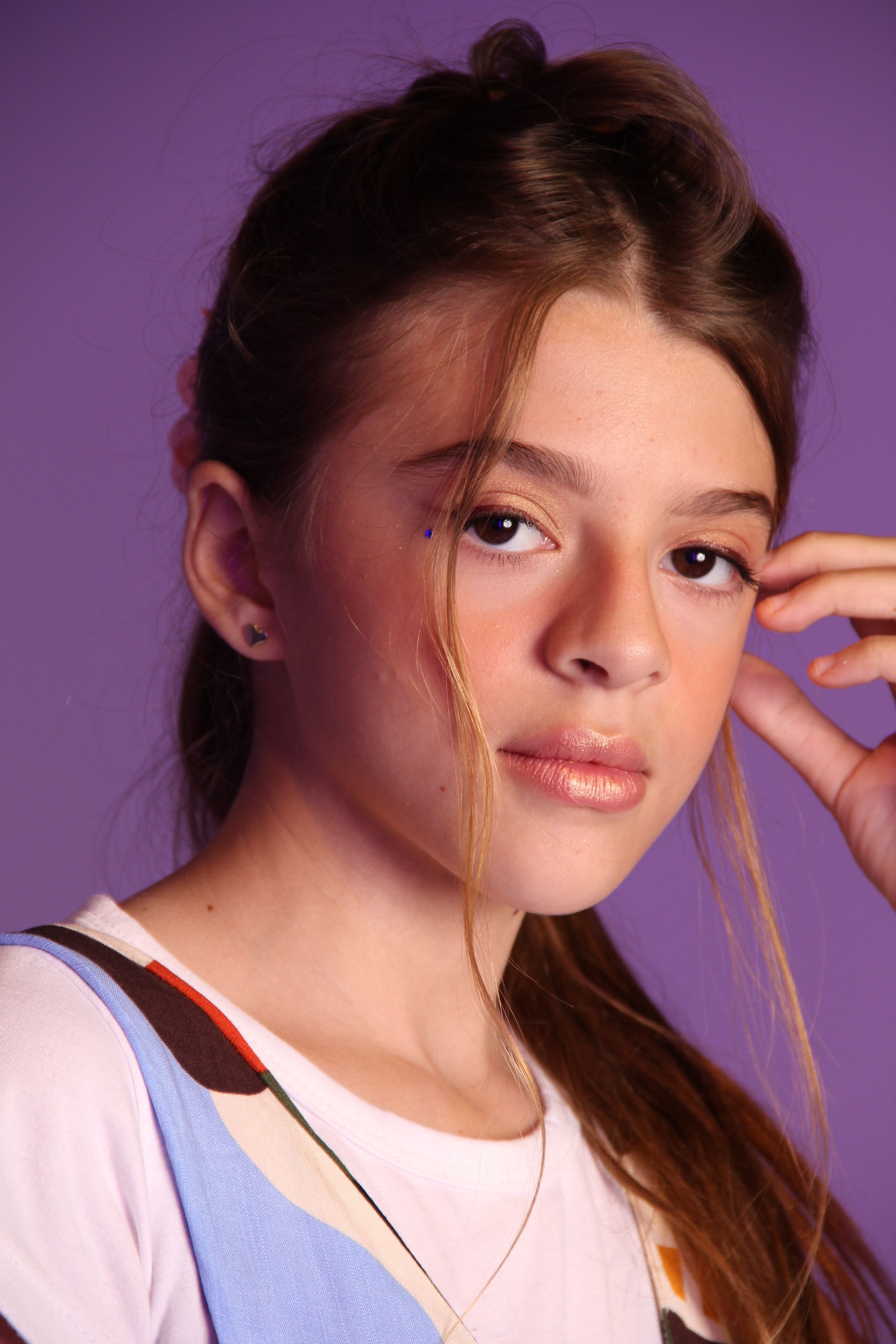 Captivating portrait of a teenage girl with brown hair against a purple backdrop.
