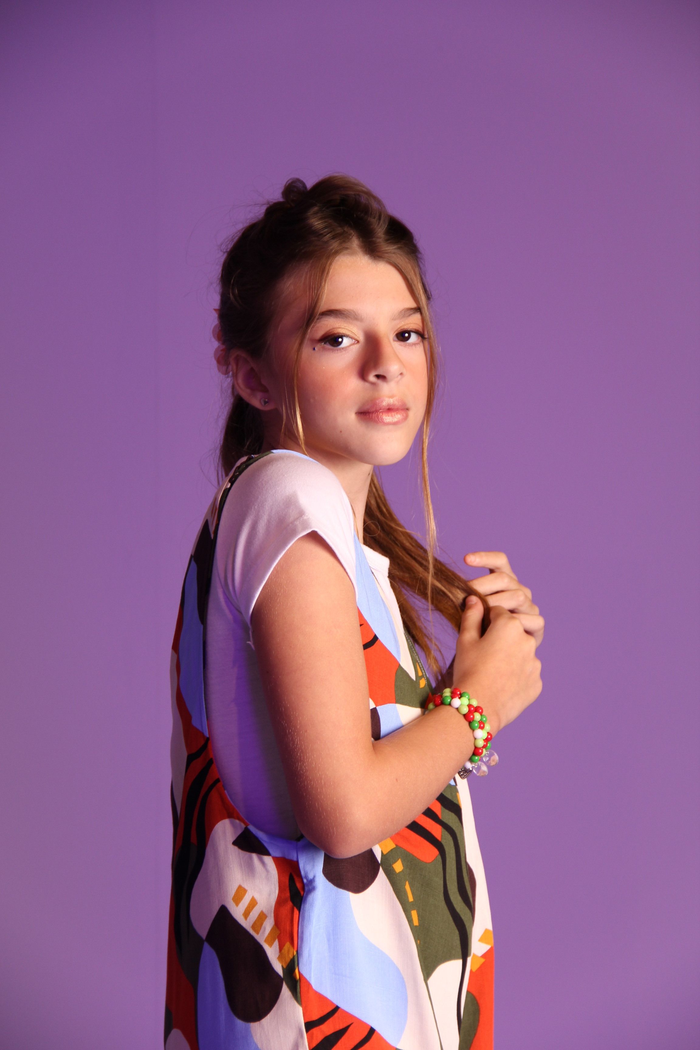 Youthful fashion portrait of a teenager against a purple backdrop, showcasing vibrant style.