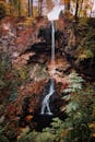 一道风景秀丽的瀑布从岩石悬崖上滑落，四周环绕着充满活力的秋叶