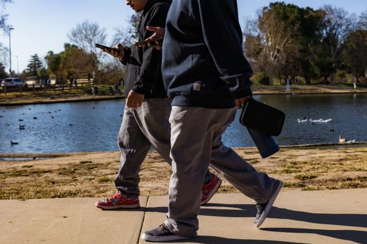 Men with Smartphones Walking along River