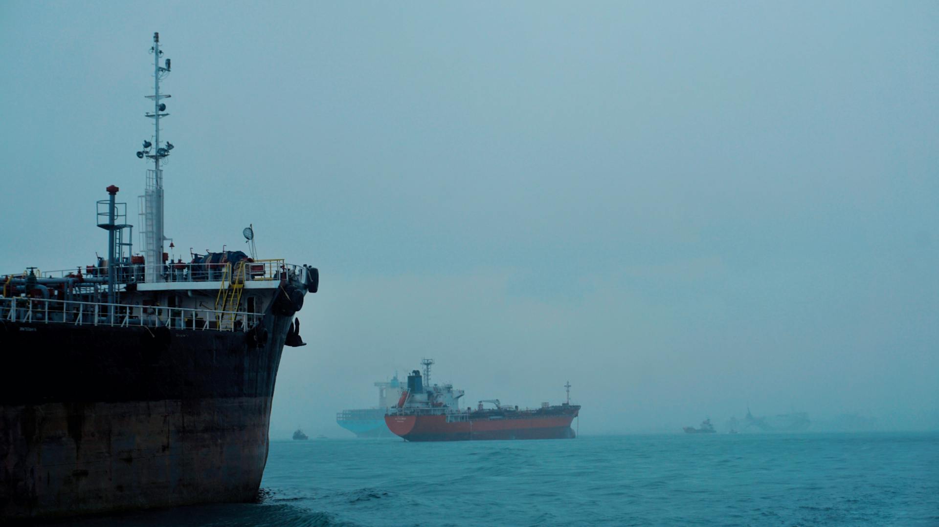 Cargo ships navigate a foggy ocean, highlighting global logistics and transportation.