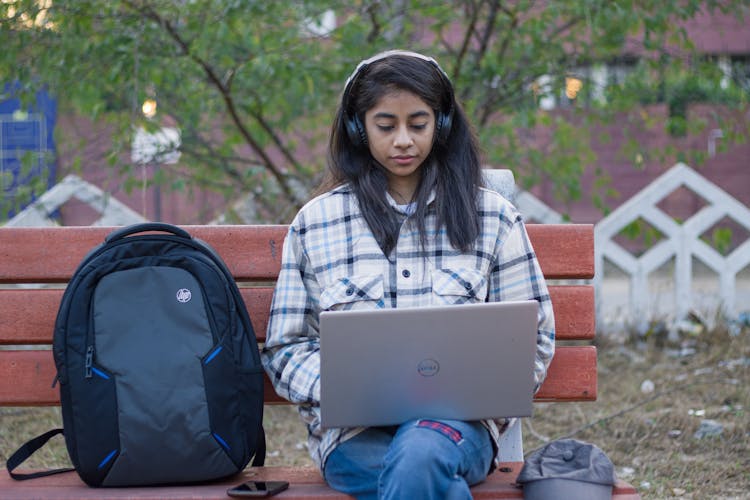 A Woman With Headphones Working On Her Laptop