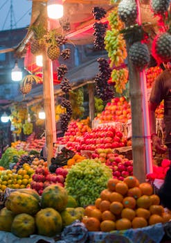 Vibrant display of fresh fruits at a lively outdoor market stall during dusk.