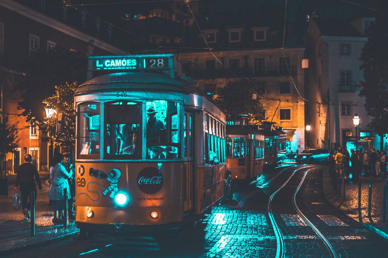 Tram 28 passing through a narrow Lisbon street lined with colourful buildings