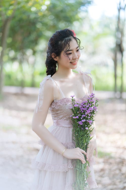 A Girl Smiling while Holding Purple Flowers