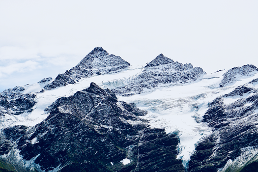 A stunning aerial view of snow-covered alpine mountains under a clear sky.