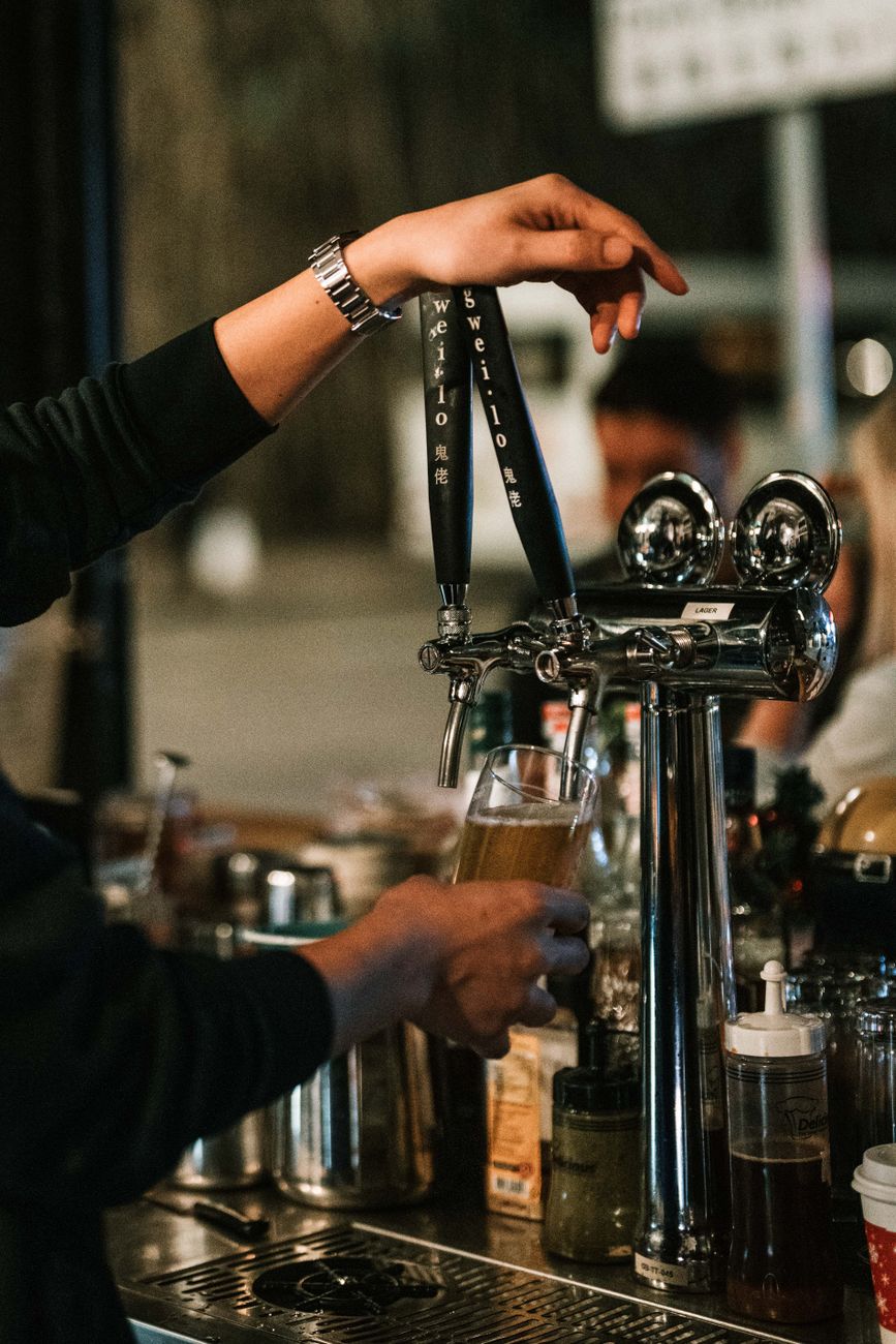 A bartender pouring a fresh beer, the point where one easy round can start to look expensive.