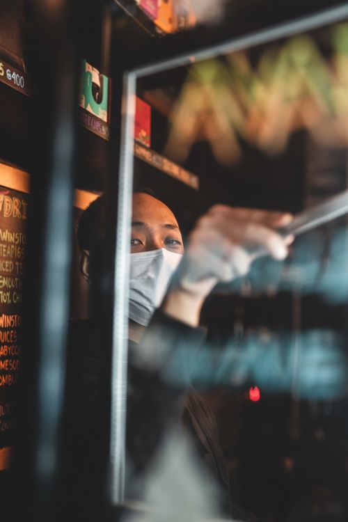 Free A barista wearing a mask prepares coffee in a Hong Kong café, promoting hygiene and safety. Stock Photo