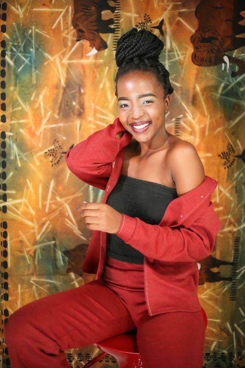 Free Vibrant portrait of a woman in stylish red attire with a joyful smile against an artistic backdrop. Stock Photo