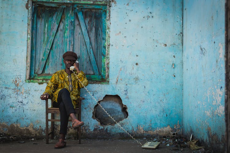 Man Sitting In Front Of Abandoned House