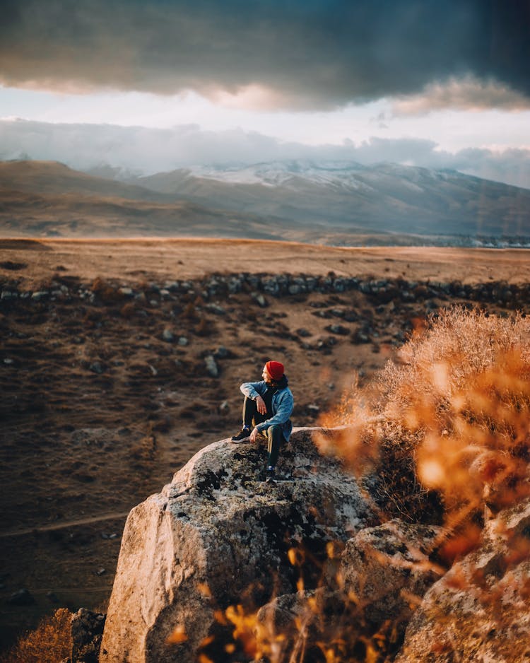 Man Sitting On Rock And Looking At Landscape