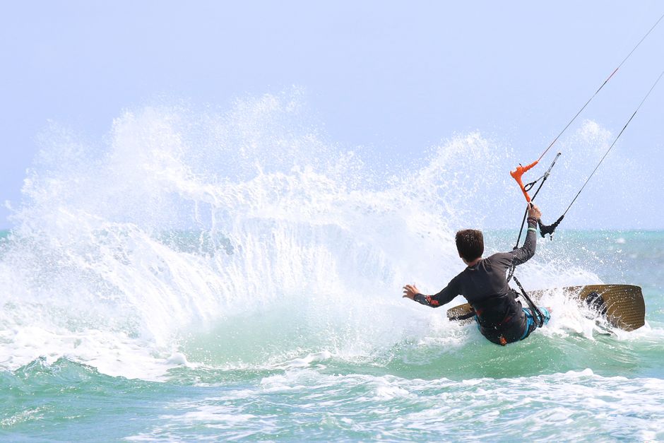 An exhilarating kiteboarding scene capturing dynamic motion and ocean waves under a clear sky.