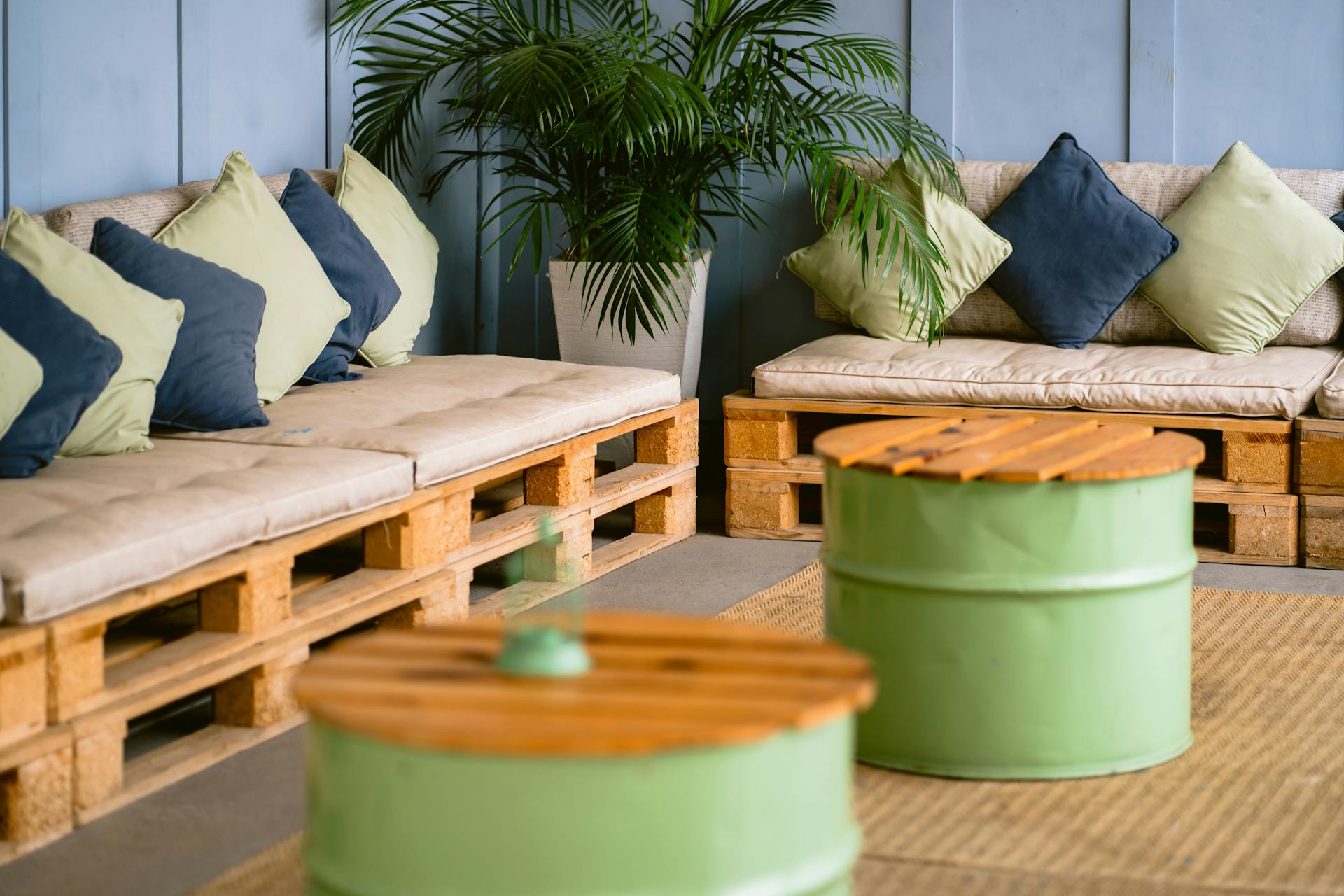 Relaxing indoor pallet sofa setup with colorful pillows and greenery for a modern touch.