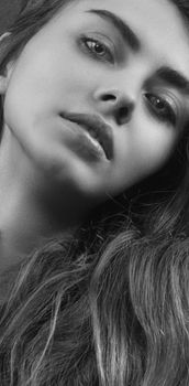 Striking black and white close-up of a young woman, capturing elegance and beauty.