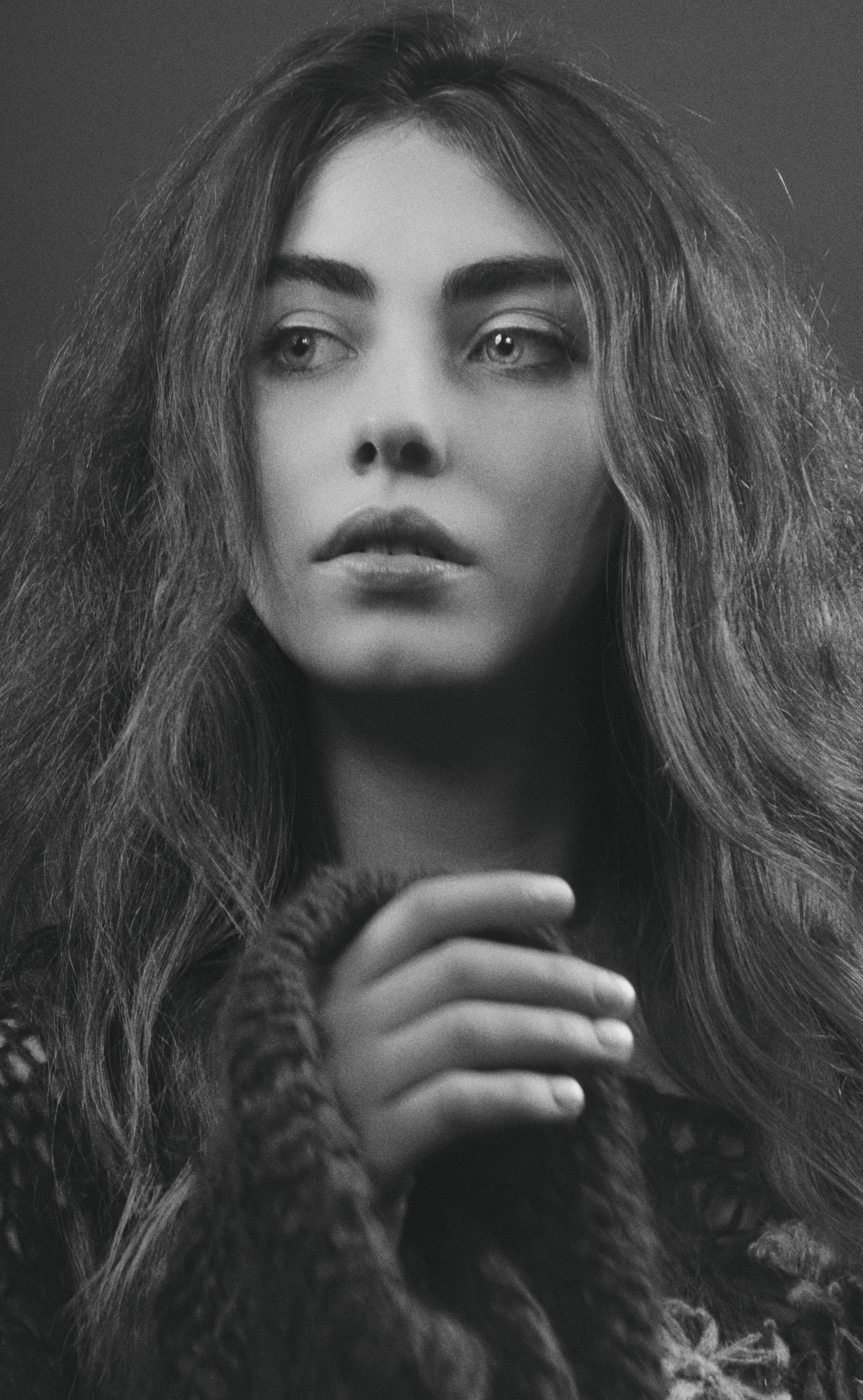 Elegant black and white studio portrait of a young woman wearing a cozy sweater.