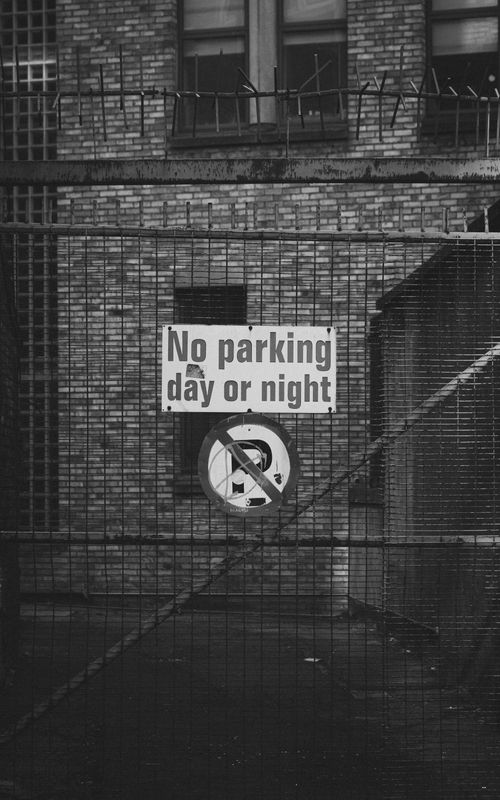 Free A black and white photo of a 'No Parking' sign on a fence in Dublin, Ireland. Stock Photo