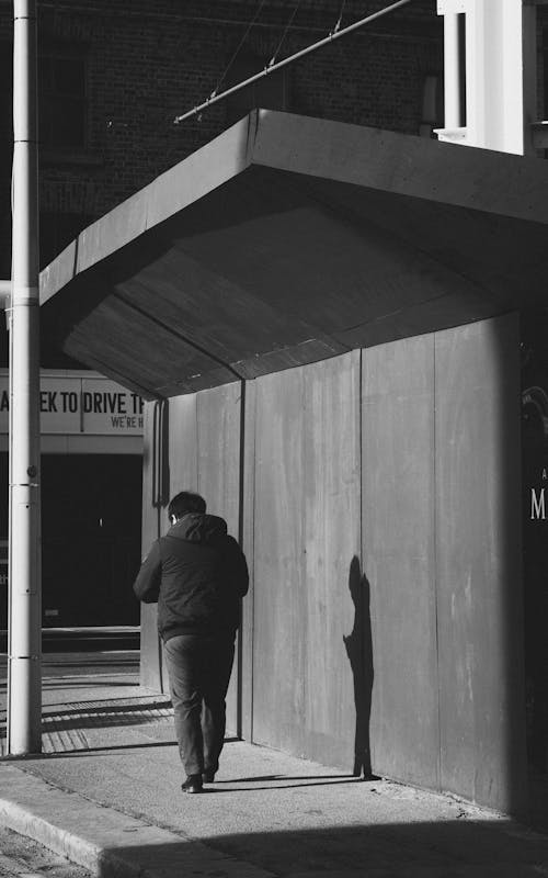 Man Walking on Sidewalk in Black and White