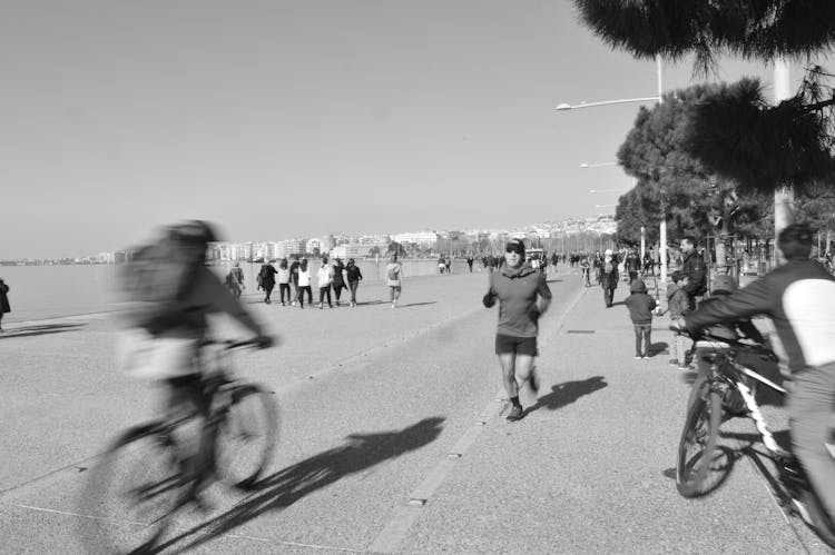 People Jogging, Walking And Cycling On Promenade