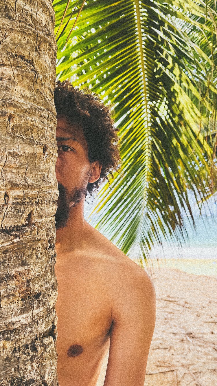 A Shirtless Man Hiding Behind A Tree 