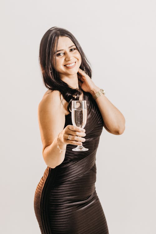 Brunette Woman Posing in a Black Leather Dress with a Glass of Champagne