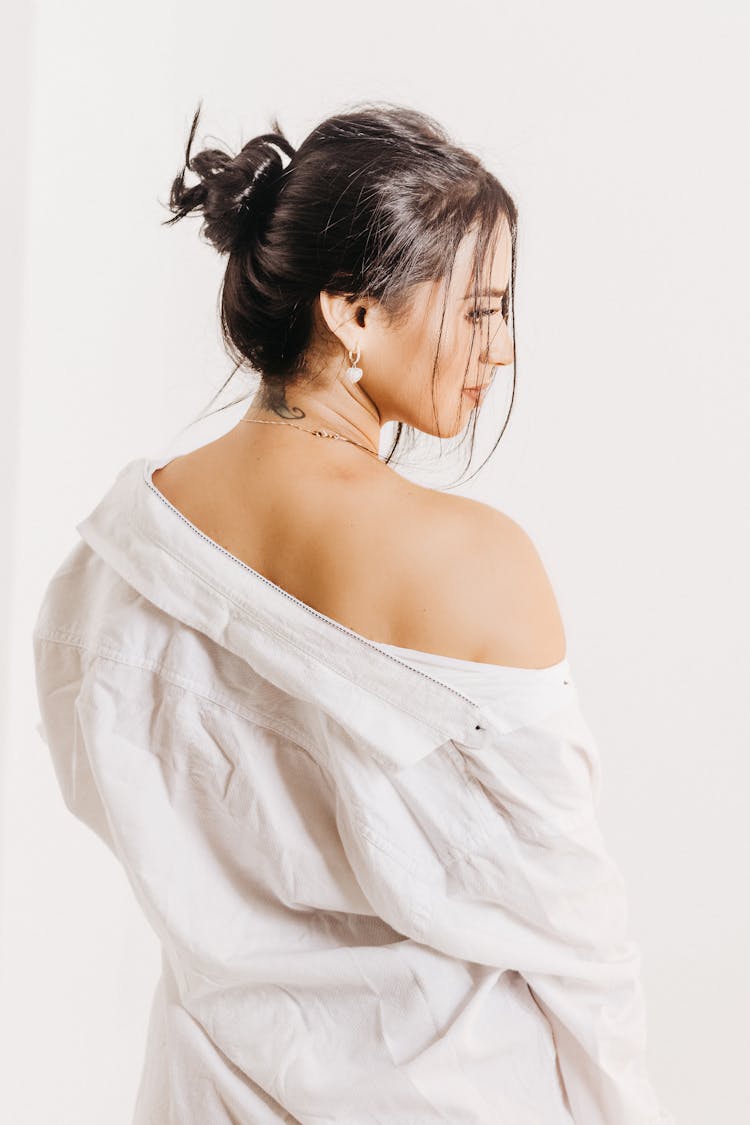 Back View Of A Brunette Woman Wearing A White Shirt Posing Against White Background