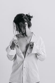 Black and white portrait of a woman in a white shirt posing sensually with a minimalist background.