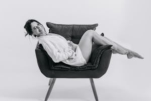Black and White Photo of a Woman Posing on an Armchair