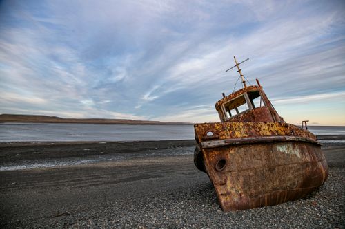 Free Abandoned rusty shipwreck on a pebbled beach at Río Gallegos, Santa Cruz, Argentina with dramatic sky. Stock Photo