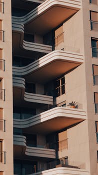 Close-up of a modern high-rise building featuring stylish balconies under warm sunlight.