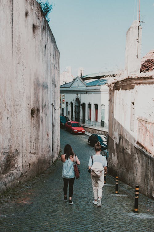 Two Woman Standing Between Buildings Under Blue Sky