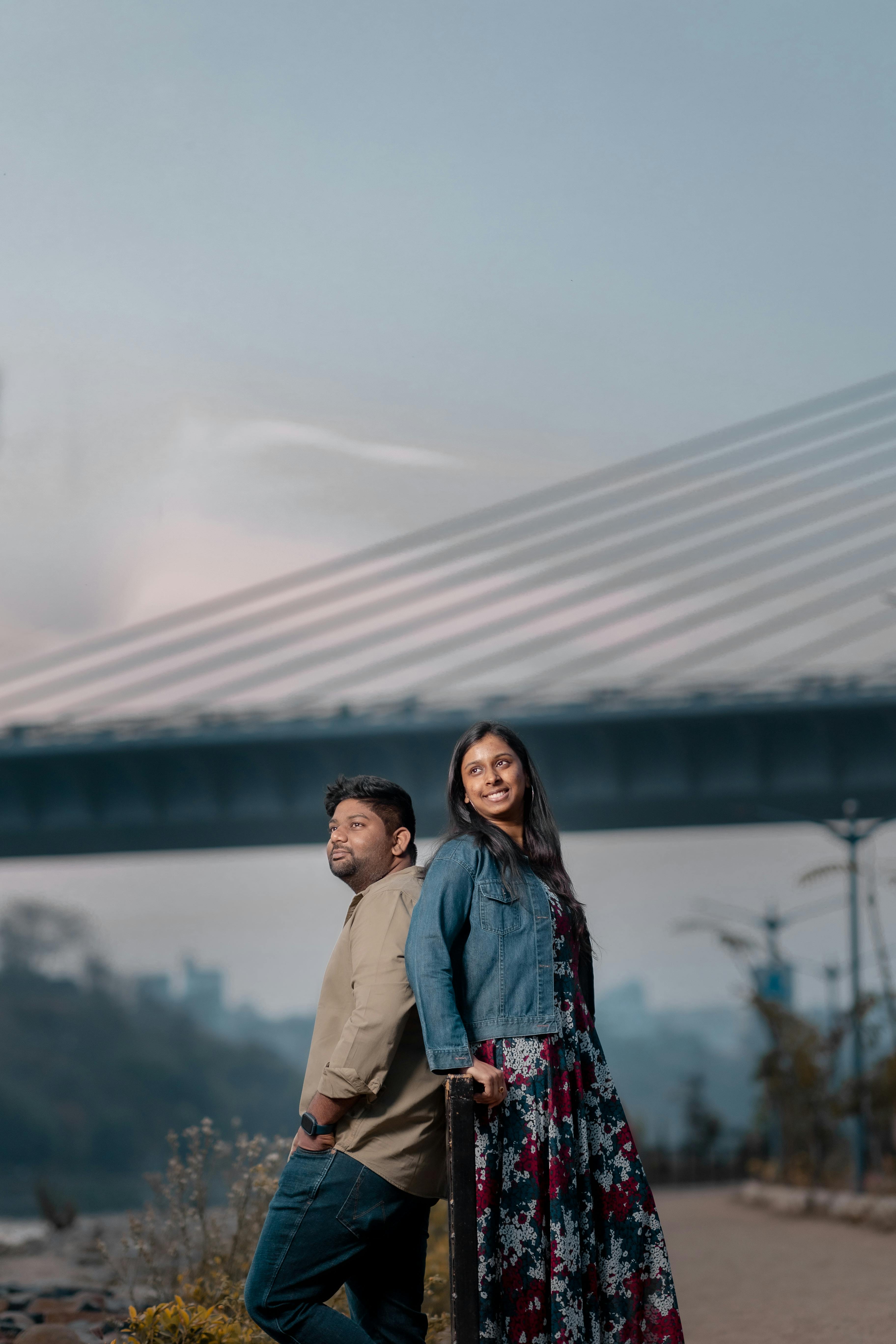 free photo of smiling couple posing near bridge