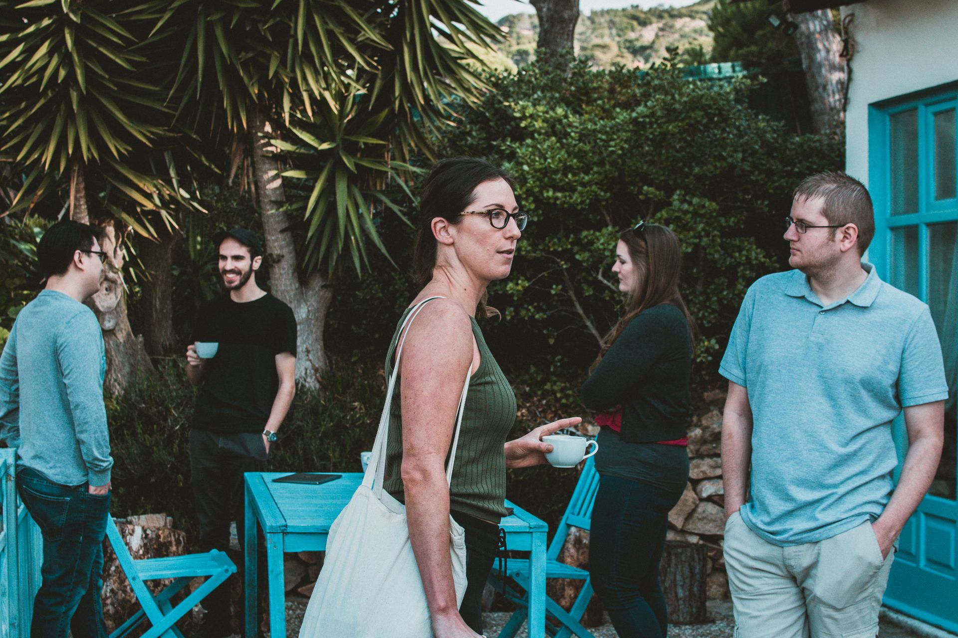 A group of friends enjoying a casual outdoor gathering at a patio with drinks and laughter.