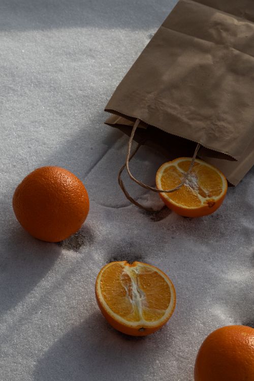 Free Fresh oranges and paper bag resting on a snowy surface, capturing winter freshness. Stock Photo