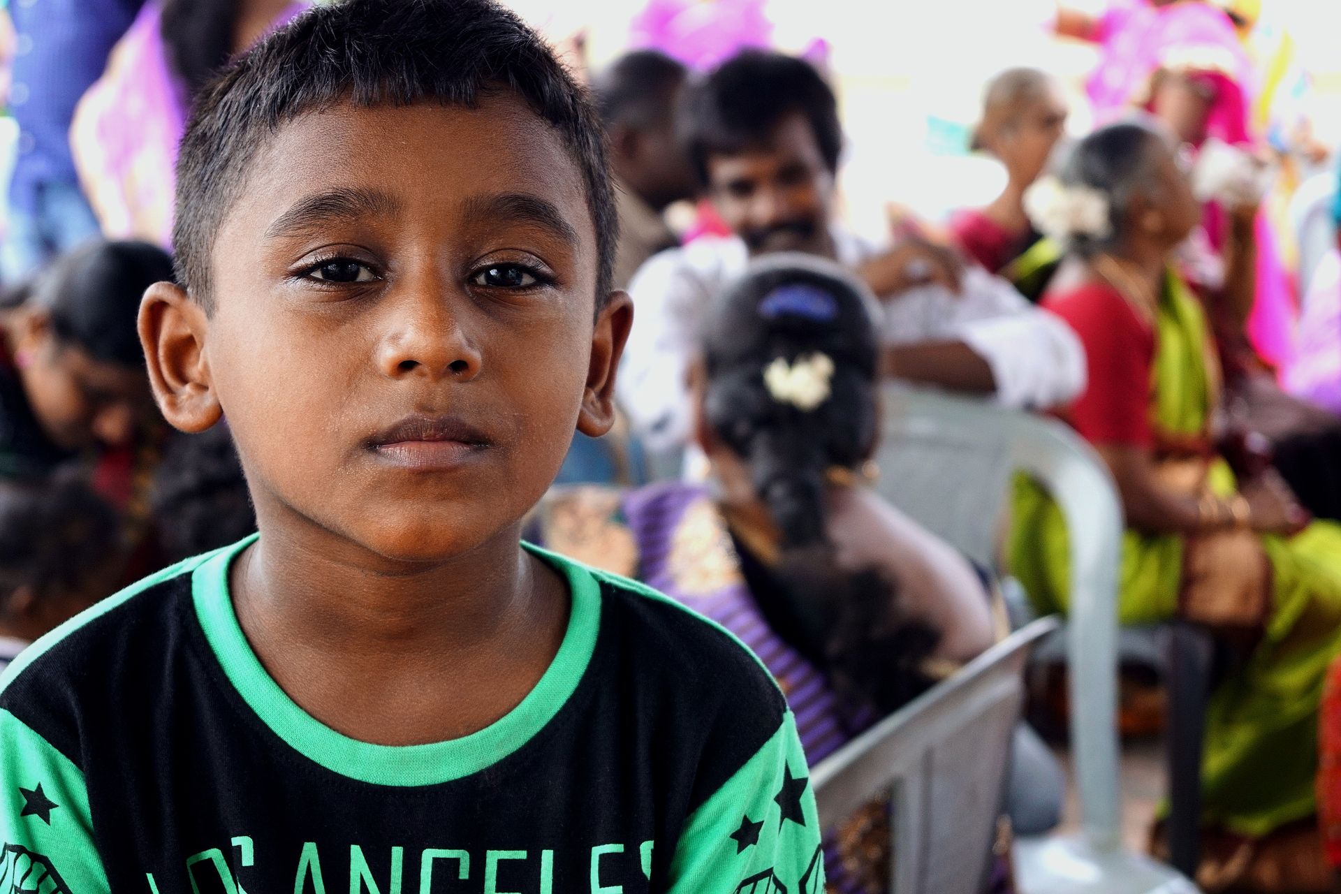 A thoughtful child attending a colorful community event with diverse participants.