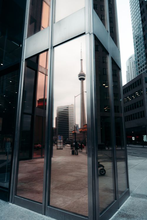 Free The CN Tower is beautifully reflected in a glass building in downtown Toronto, capturing urban elegance. Stock Photo