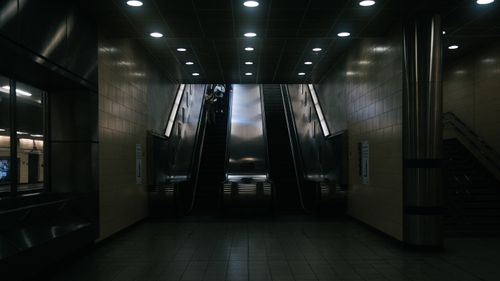 Free A dimly lit underground station featuring a pair of escalators in a modern setting. Stock Photo