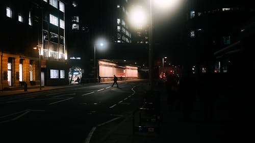 A person is walking down a street at night