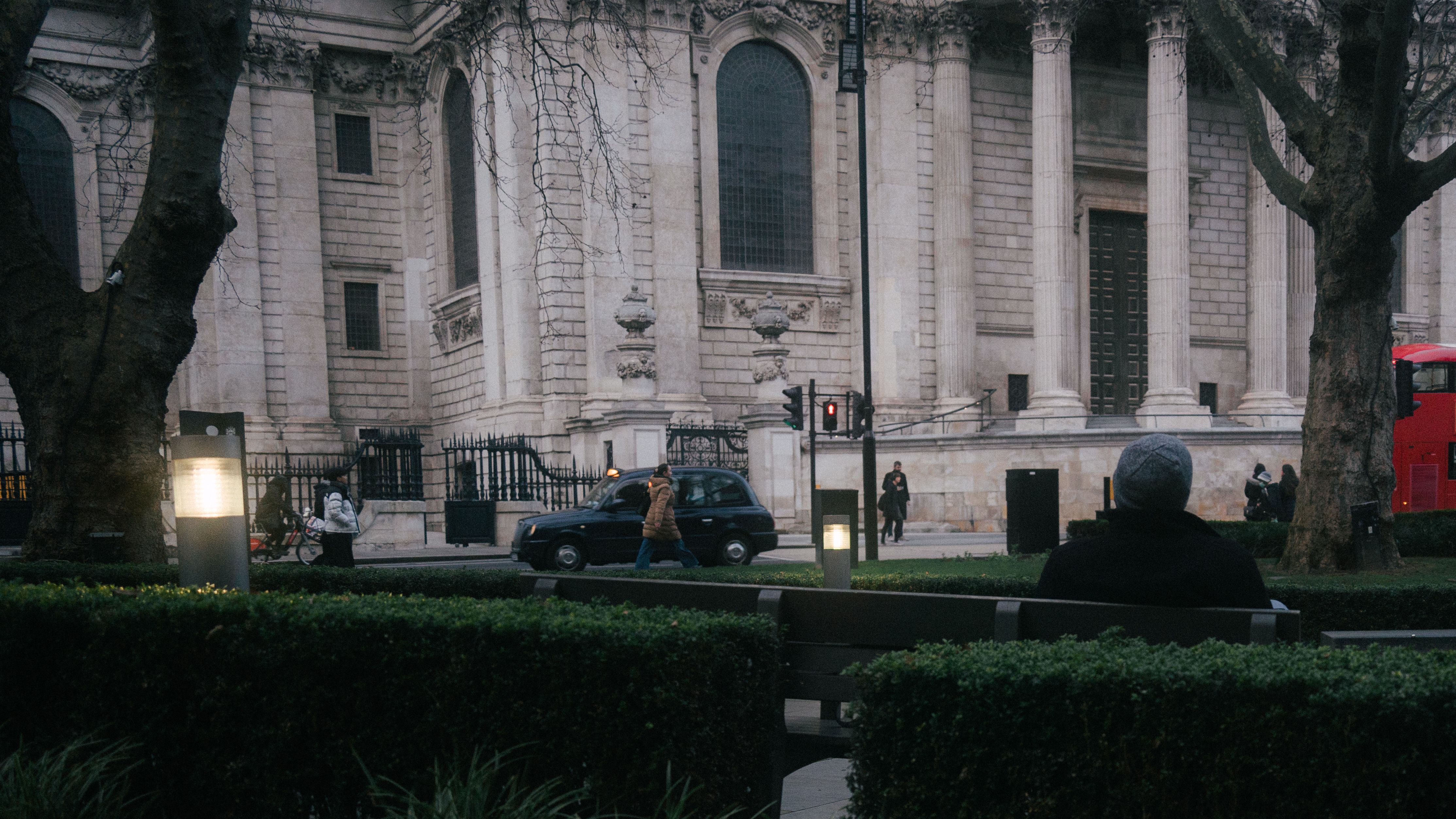 Peaceful cityscape of St Paul's Cathedral with people walking and sitting.