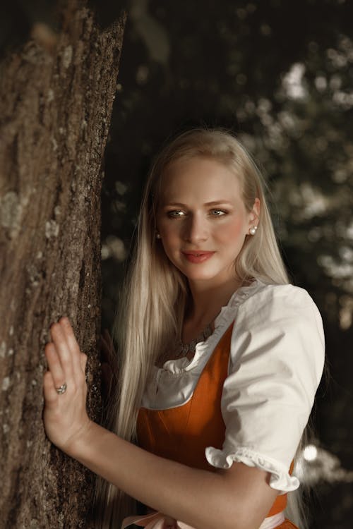 Portrait of a Pretty Blonde Touching a Tree Trunk