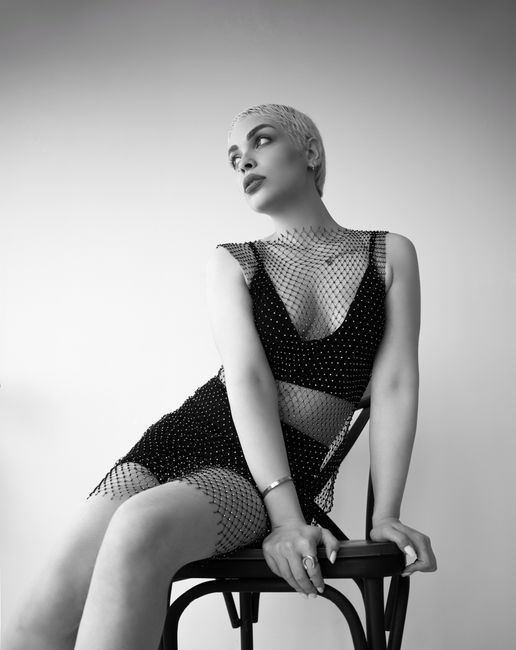 Elegant black and white portrait of a woman sitting in a stylish pose on a chair.