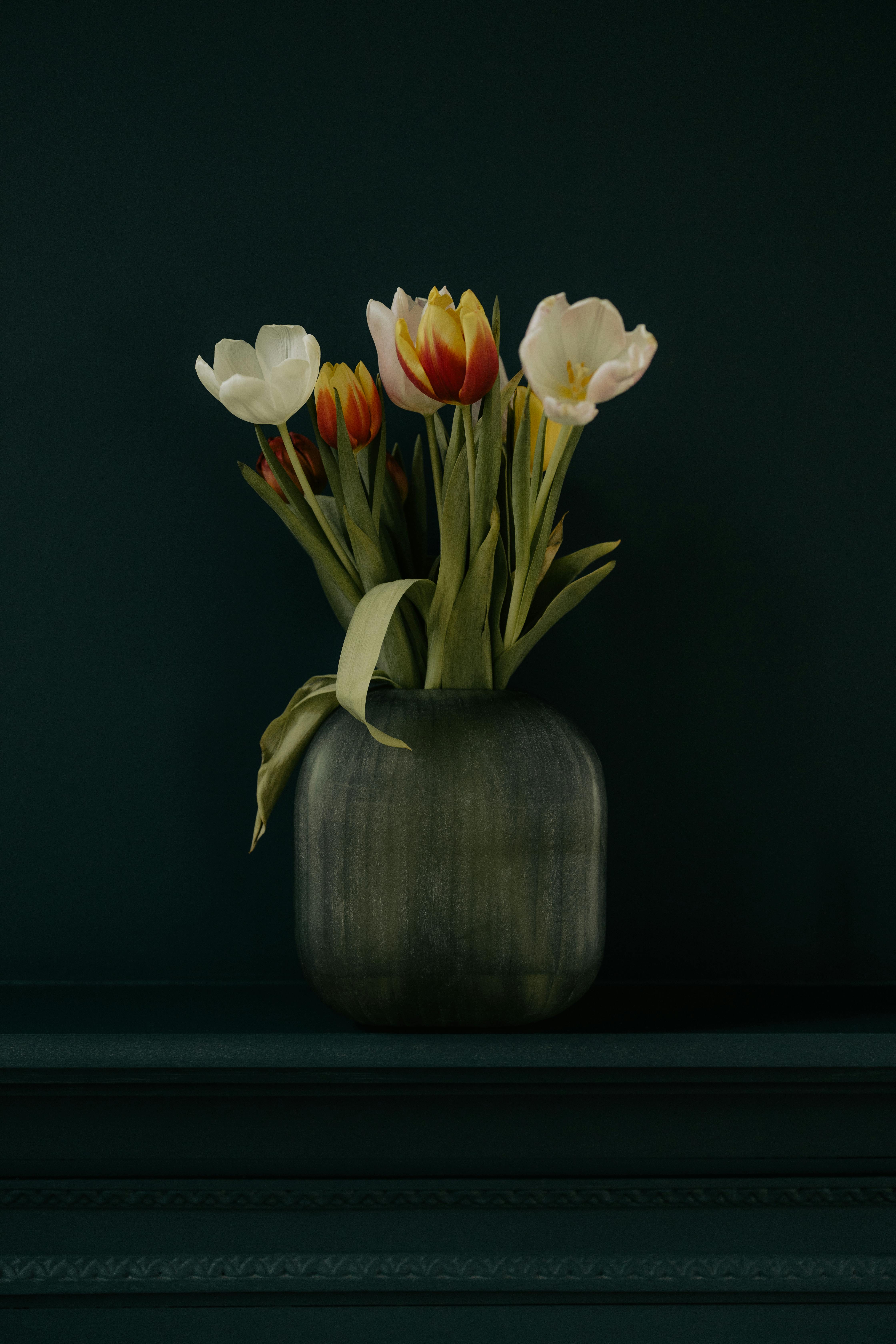 Beautiful tulip bouquet in a rustic vase against a dark background, perfect for decor inspiration.