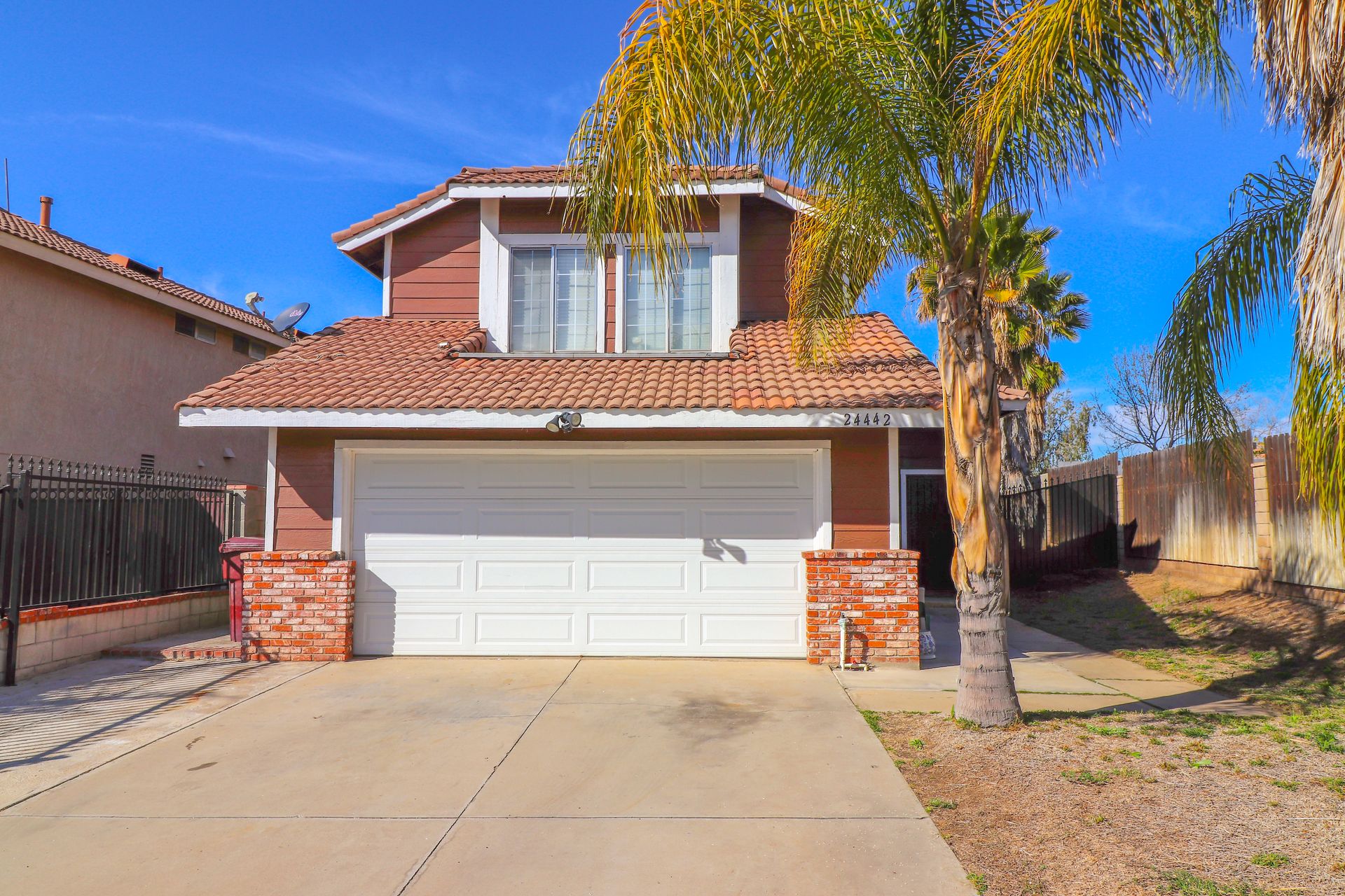 Two-story home with a wide garage door and a palm tree