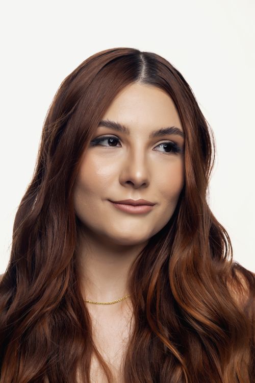 Free A confident woman with long brown hair poses with a gentle smile against a white background. Stock Photo