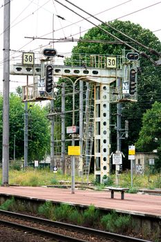 Detailed view of railway signal structure at a railway station with traffic lights and platform.