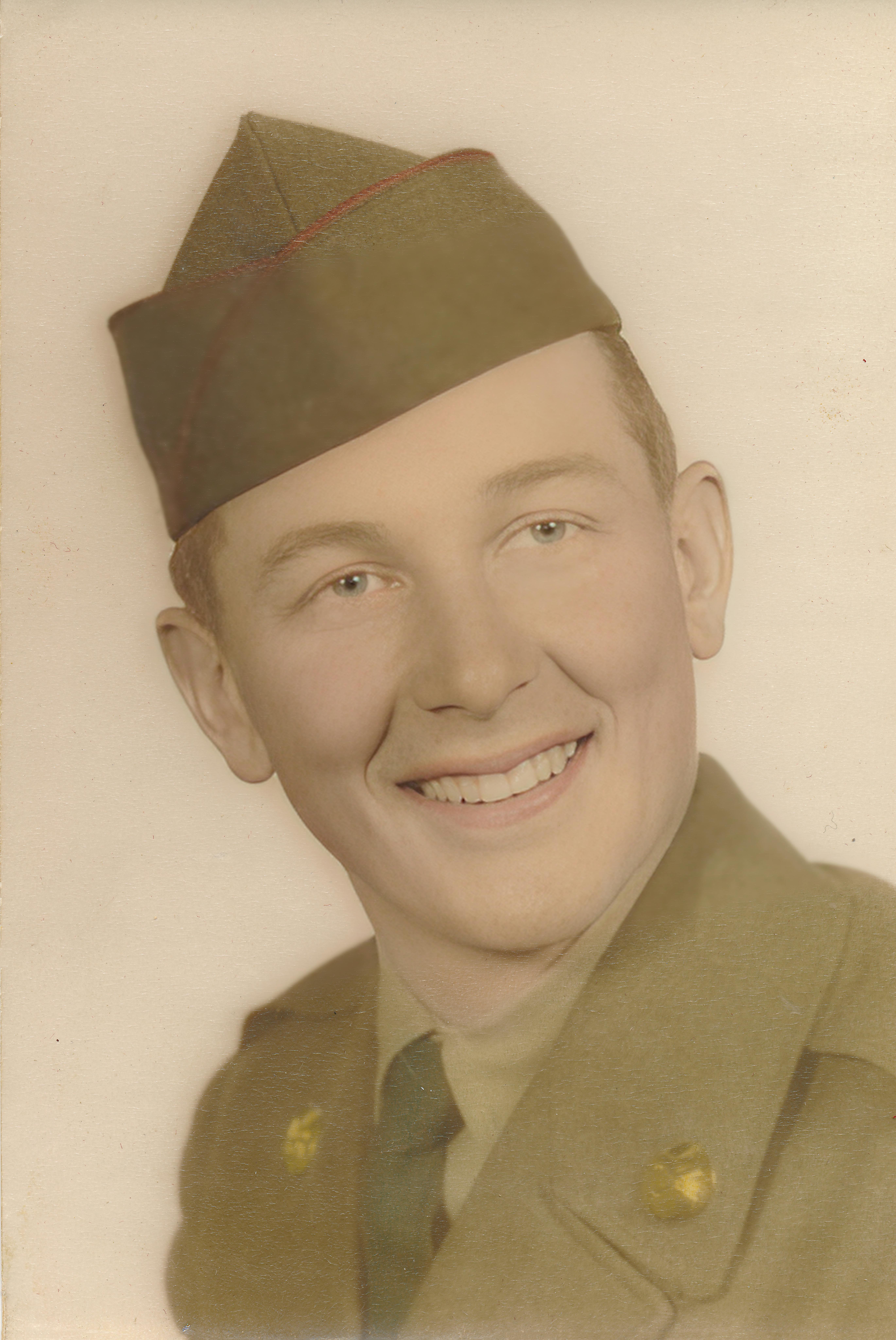 A classic sepia portrait of a smiling soldier in military uniform wearing a hat.