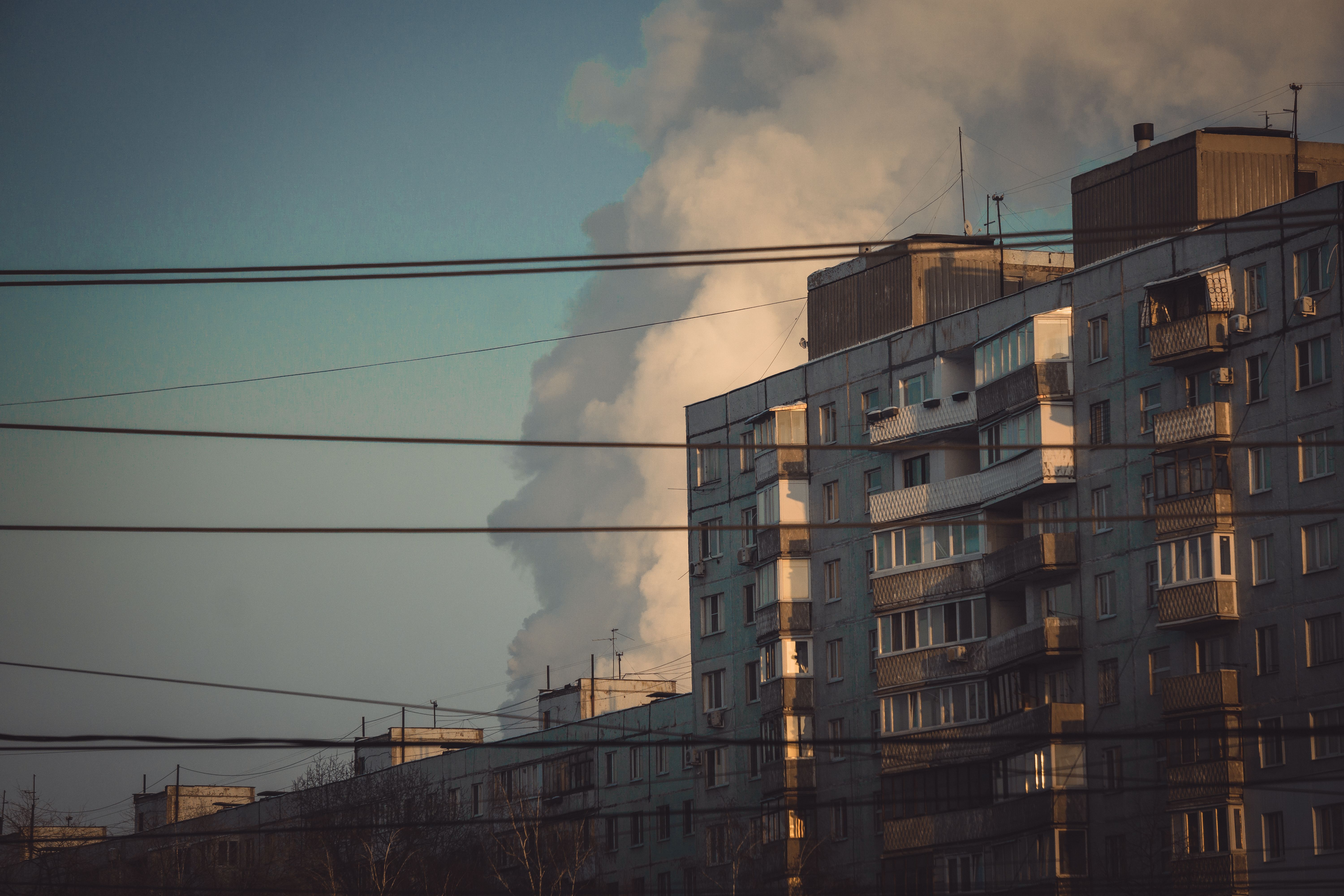 A cityscape with high-rise buildings and smoke clouds rising in the sky.