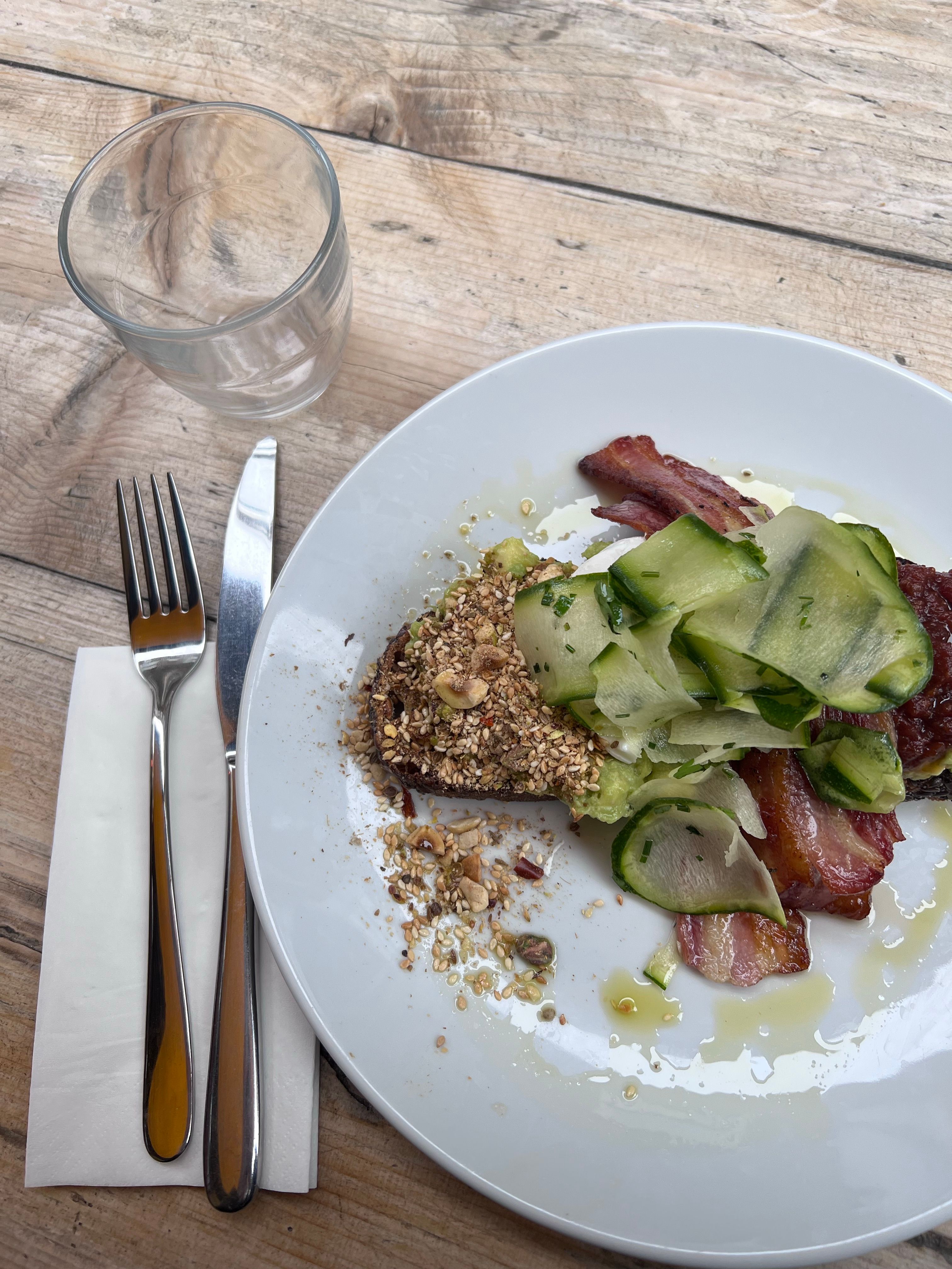 Close-up of a delicious breakfast plate with bacon, zucchini, and nuts on a wooden surface.