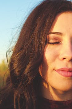 一位闭着眼睛的女人，在温暖的日光下，黑发飘逸