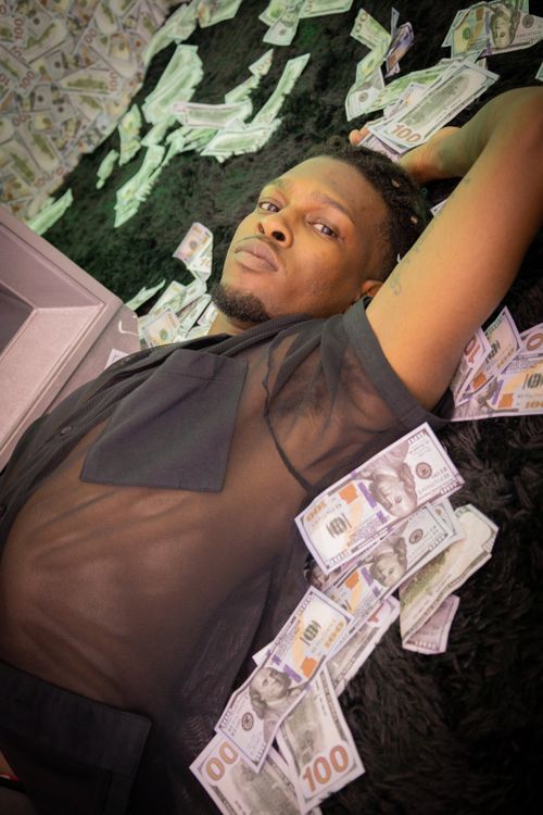 Free A young man lies on a pile of US dollars, exuding luxury and wealth. Stock Photo